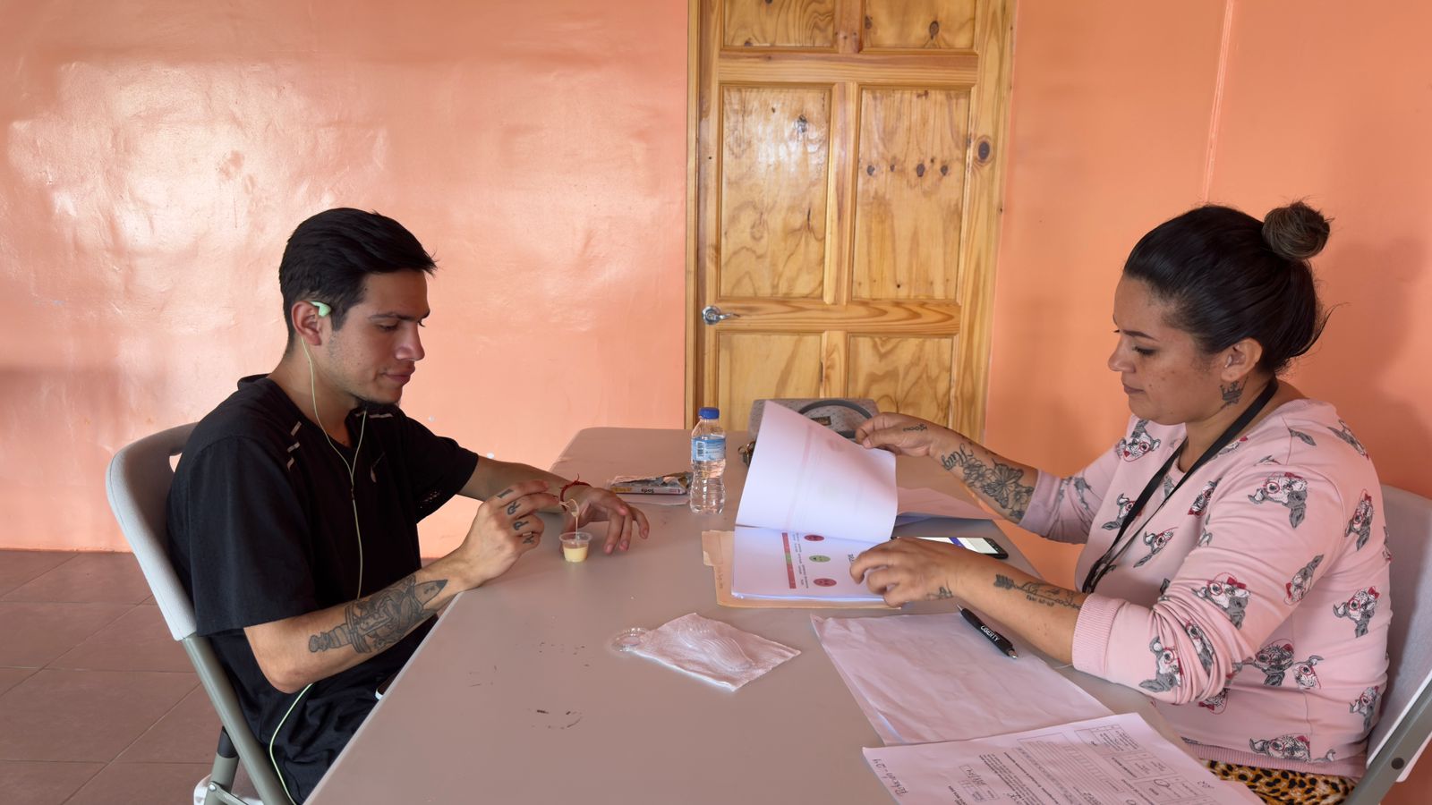 Market Research in Central America Participant and interviewer at a table with a sample cup and printed evaluation sheets
