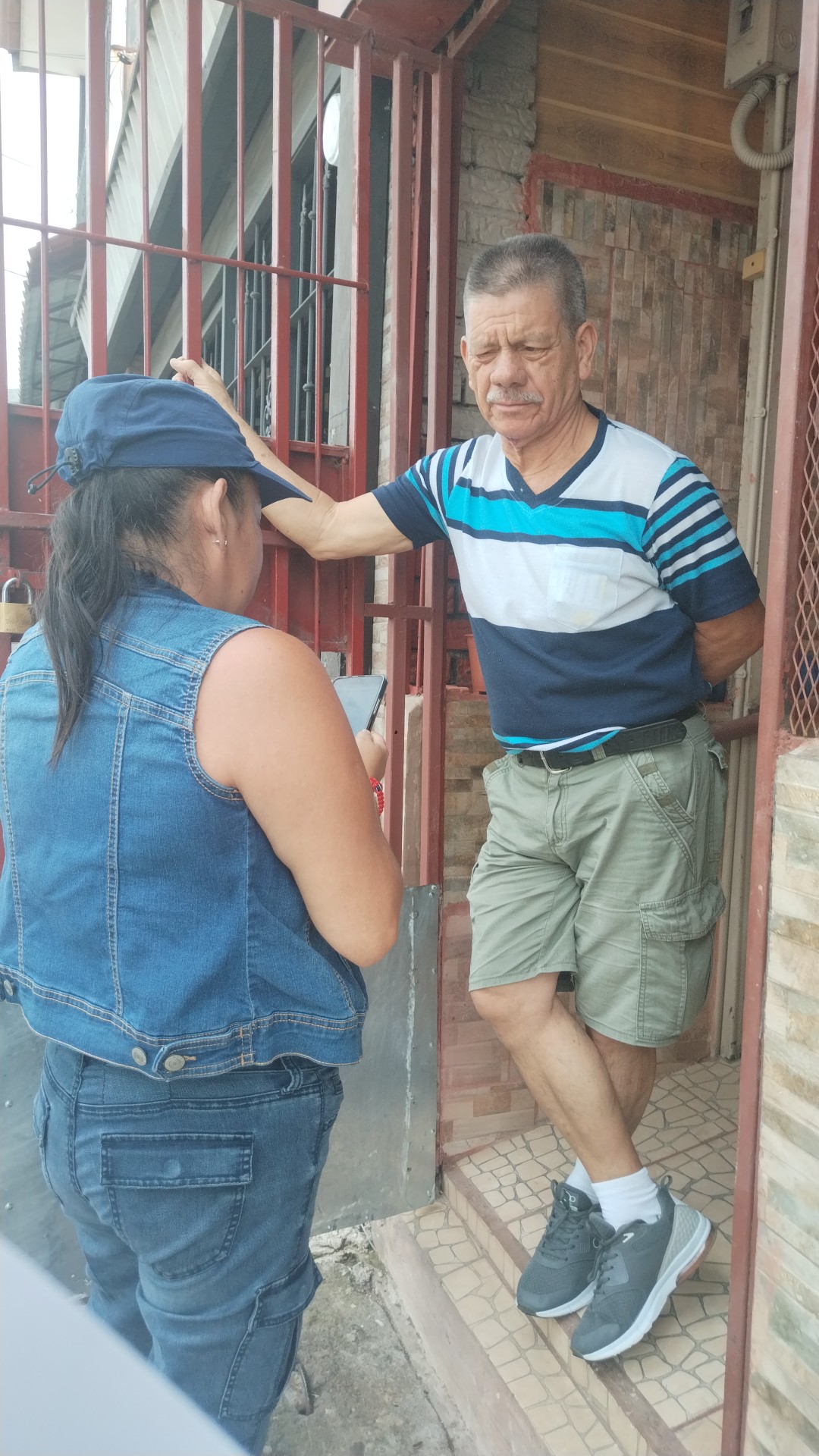 Market Research in Central America Face-to-face interaction at a doorway with a handheld device